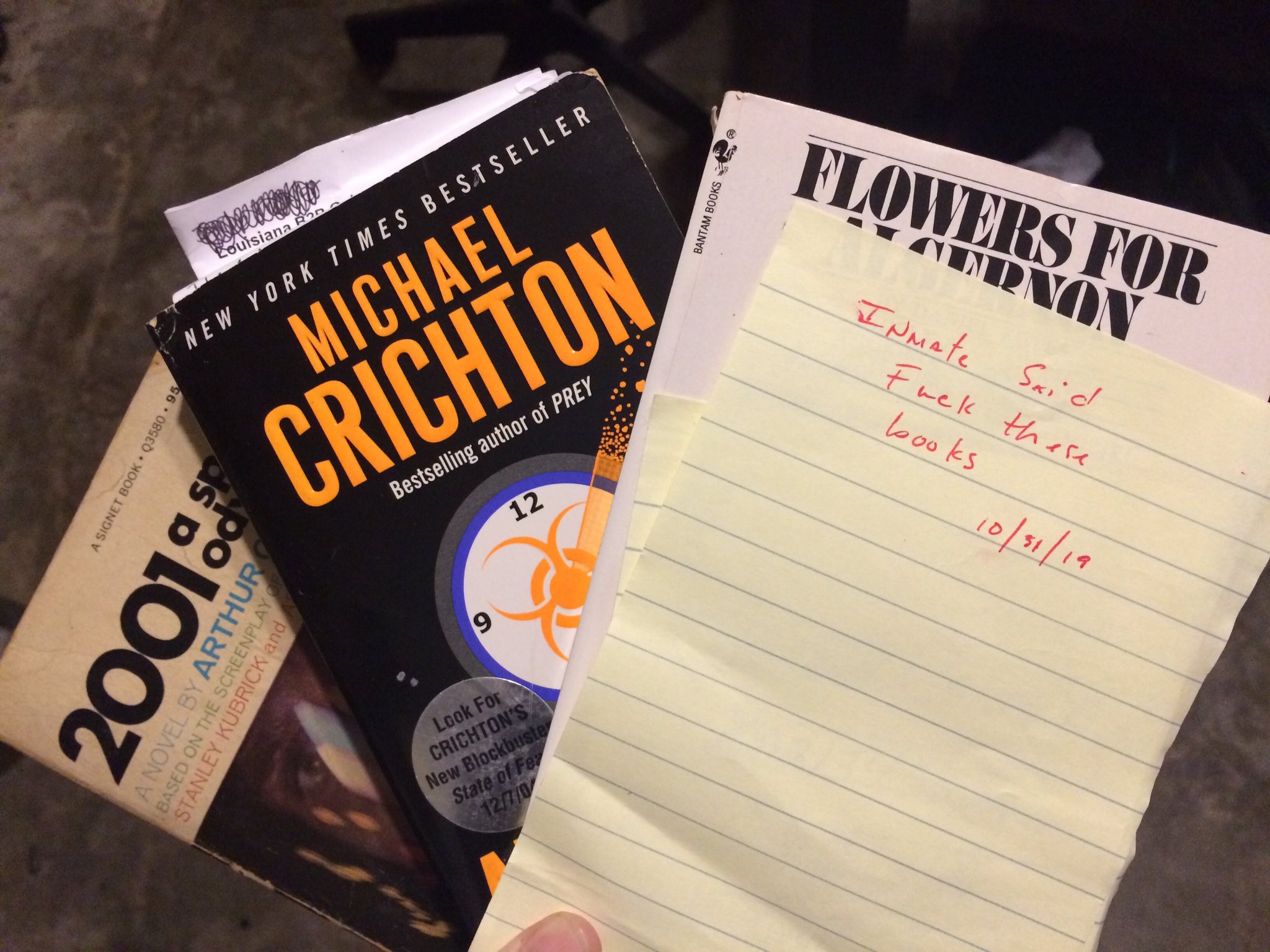 Copies of 2001: A Space Odyseey, a Michael Chrichton book, and Flowers for Algernon. A note reads: "Inmate said fuck these books. 10/31/19"